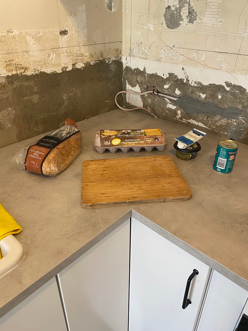 ingredients on a concrete bench top - bread, eggs, goats cheese, pesto, baked beans